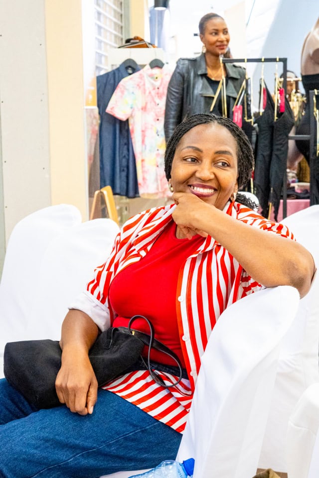 A smiling guest in a red-and-white striped jacket enjoys Style, Shop & Sip.
