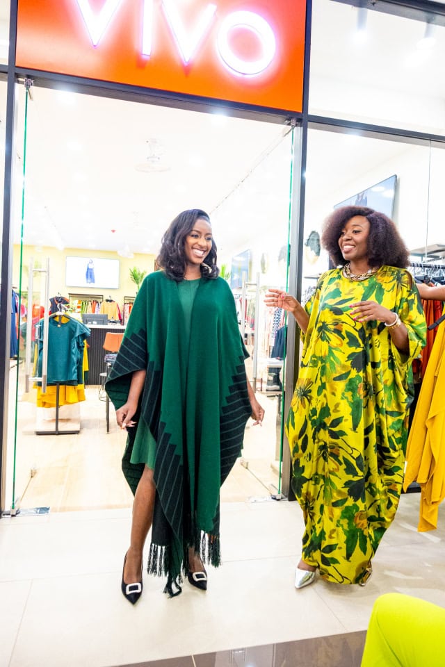 Connie Oluoch and a guest smile and talk beside clothing displays during Style, Shop & Sip at Galleria Shopping Mall.