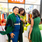 Guests engage with a green fashion look as Connie Oluoch styles an attendee during Style, Shop & Sip
