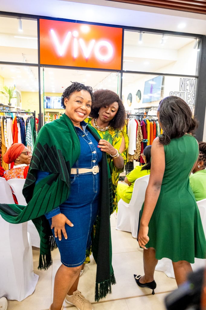Guests engage with a green fashion look as Connie Oluoch styles an attendee during Style, Shop & Sip