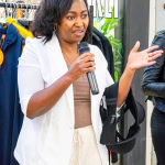 A speaker gestures while addressing guests at the Style, Shop & Sip event.