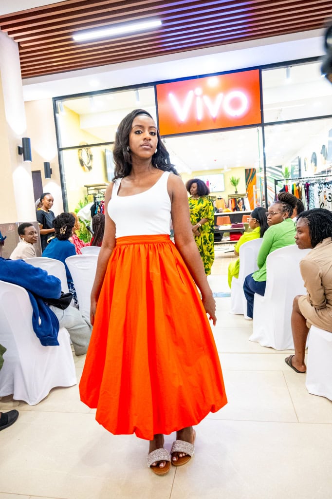 A fashion participant models a white top and bright orange skirt during Style, Shop & Sip