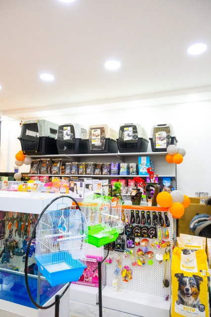 Wide view of a brightly lit pet store interior with aquariums, cages, food, and pet accessories