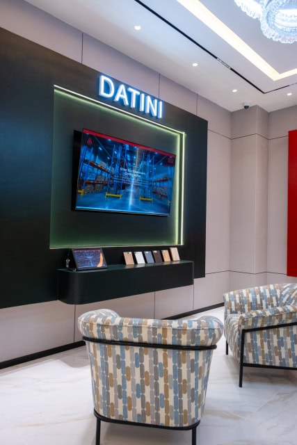 ASHUT showroom display wall labeled DATINI with a television, material samples, and patterned seating.