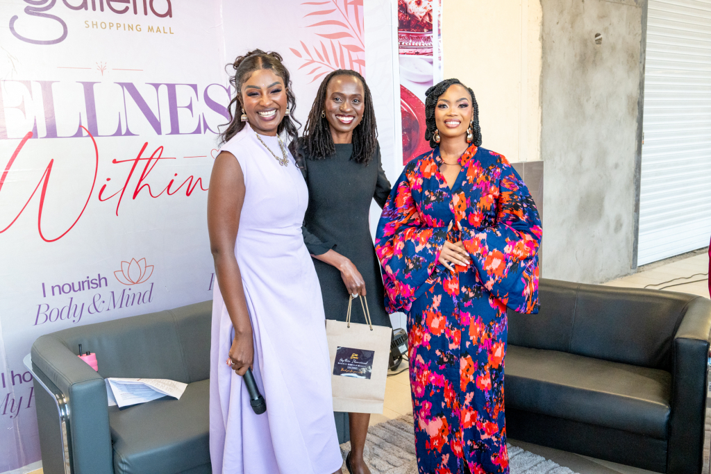 Three women posing together in front of a Wellness Within event backdrop.