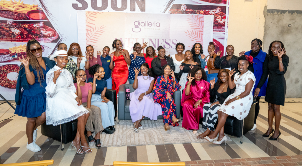 A large group of women pose together in front of a Galleria Wellness event backdrop.