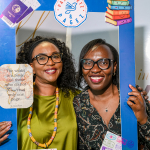 Guests Use the Travelling Book Club Photo Frame Two smiling women posing behind a blue travelling book club photo frame