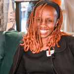 Smiling Guest Portrait A seated woman with copper braids smiles at the camera in the event space.