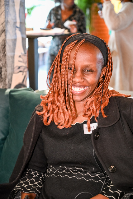 A seated woman with copper braids smiles at the camera in the event space.