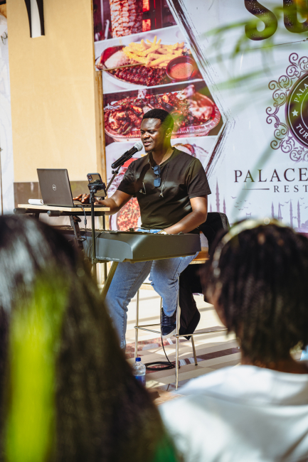 A musician performs at a keyboard while audience members watch
