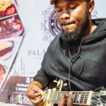 Guitarist Playing Close Up A guitarist looks down while picking the strings of a gold electric guitar