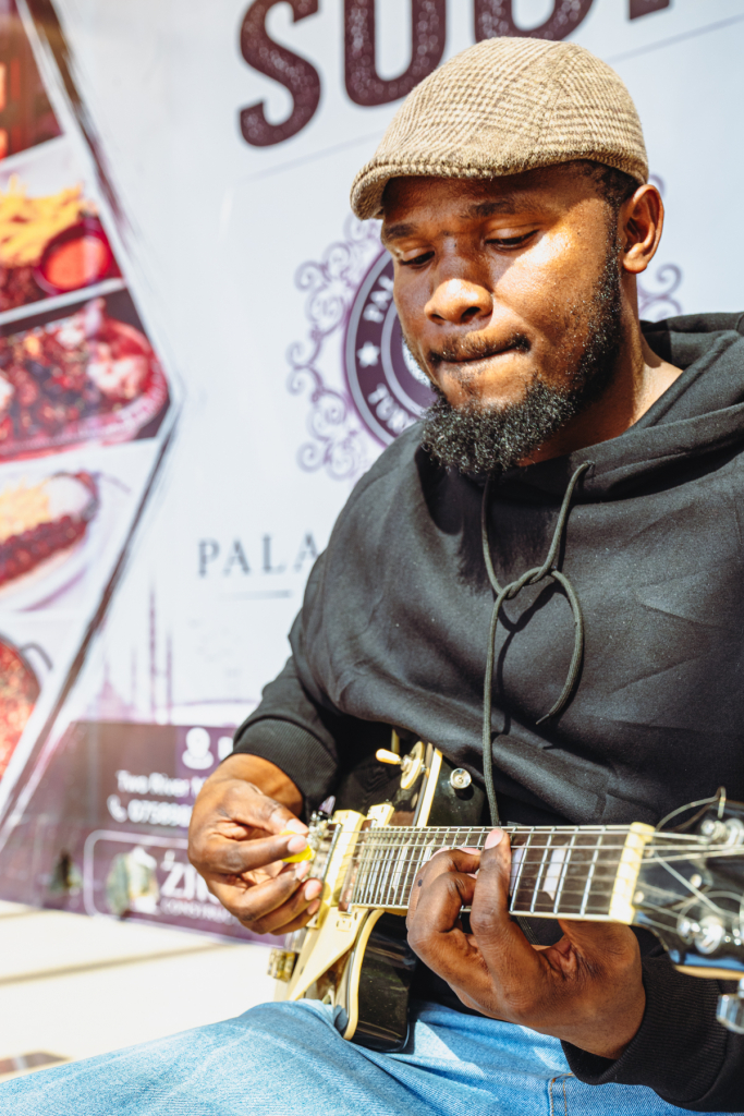 A guitarist looks down while picking the strings of a gold electric guitar