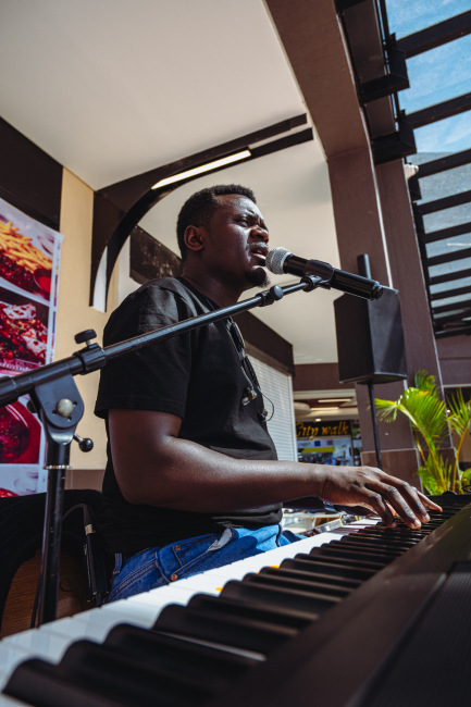 Musician singing into a microphone while playing a keyboard.