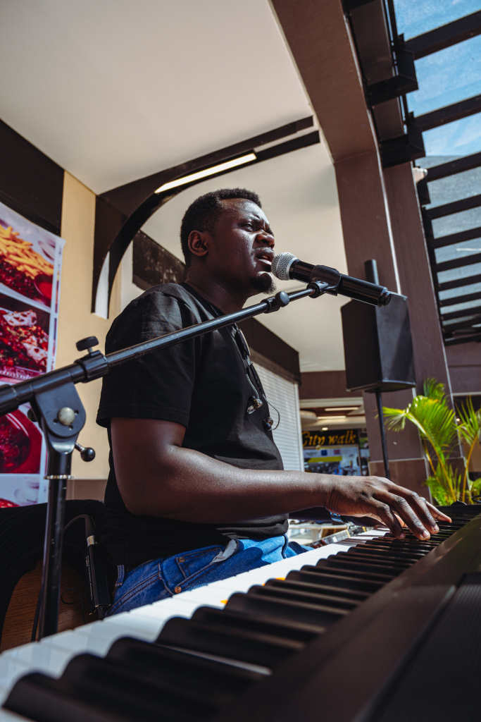 Musician singing into a microphone while playing a keyboard.