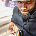 Close-Up of Stringed Instrument Player Musician in a knit cap looking down while holding a stringed instrument.