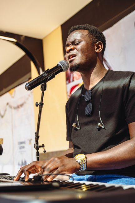Musician singing with eyes closed while playing a keyboard.