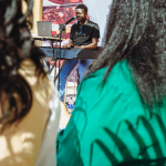 Performance Seen Through the Audience Musician performing on a small stage as seen between audience members.
