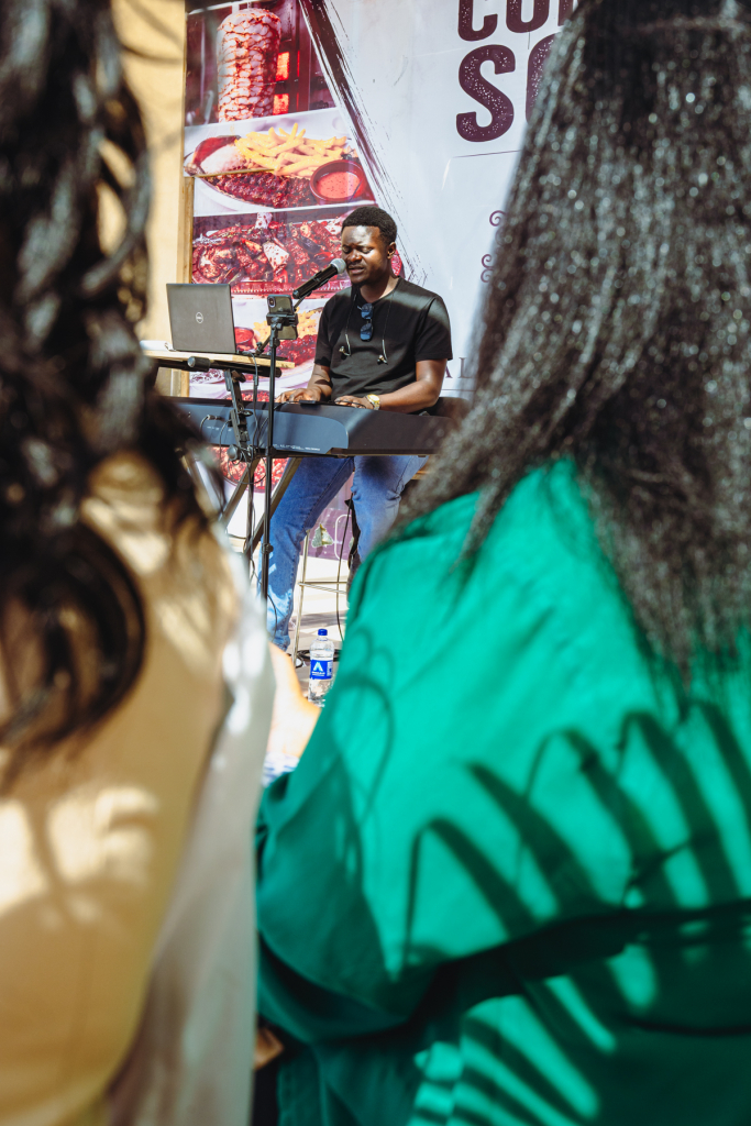Musician performing on a small stage as seen between audience members.