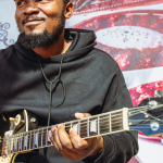 Guitarist Performing at the Mall A smiling guitarist in a flat cap plays a gold electric guitar