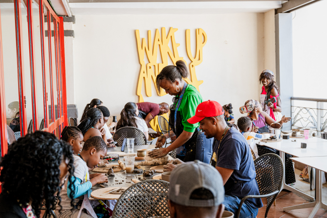 A busy group of participants making pottery together around tables
