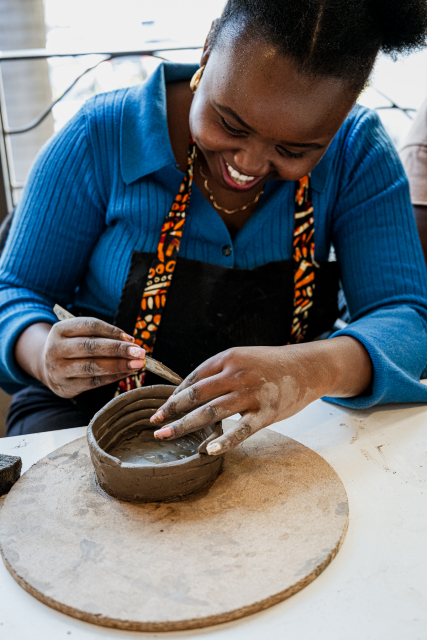 Smiling participant adds detail to a handmade clay bowl.
