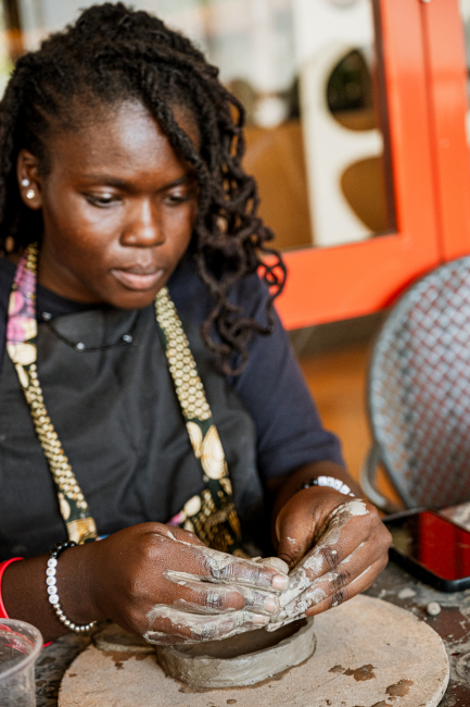 Participant concentrates while shaping clay by hand at a pottery table