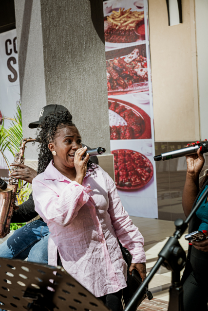 A singer in a pale pink shirt sings into a microphone during a live performance.