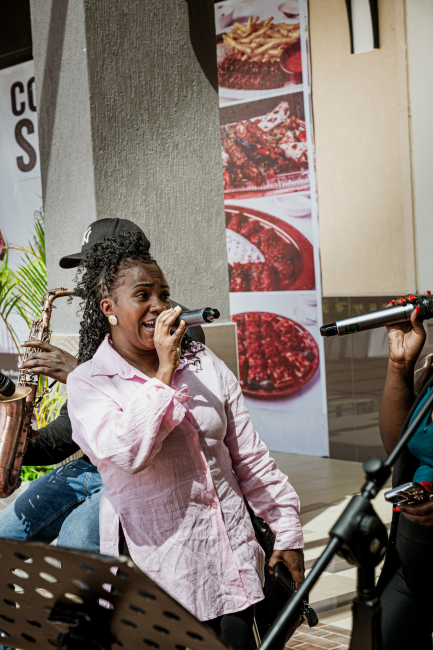A singer in a pale pink shirt sings into a microphone during a live performance.