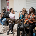 A full band performs together in a shopping mall concourse.