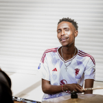 Drummer seated behind a drum kit and looking toward the camera.