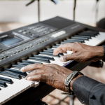 Close-up of a musician's hands playing an electronic keyboard.