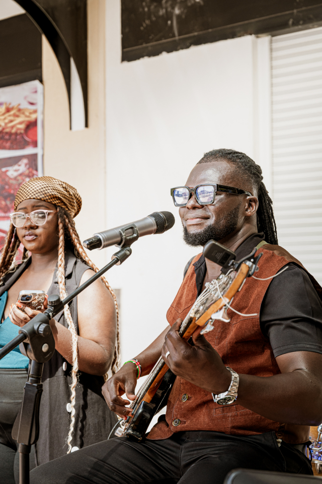 A bassist plays beside a singer during a live mall performance.