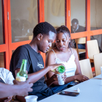 One attendee pours a green drink into another person’s cup at the event table.