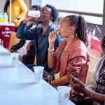 Attendees taste drinks together at a table, with branded cups in front of them.