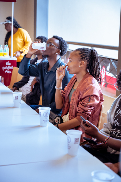 Attendees taste drinks together at a table, with branded cups in front of them.