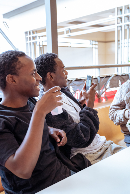 Two guests sit together holding tasting cups near the mall windows