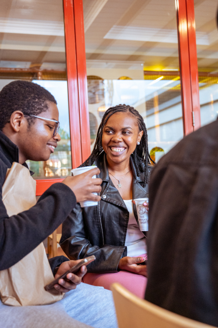 Smiling woman in a black leather jacket speaks with another guest at the table.
