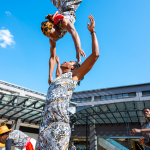 DZ6 1251 A performer is lifted overhead by another performer in the mall plaza.