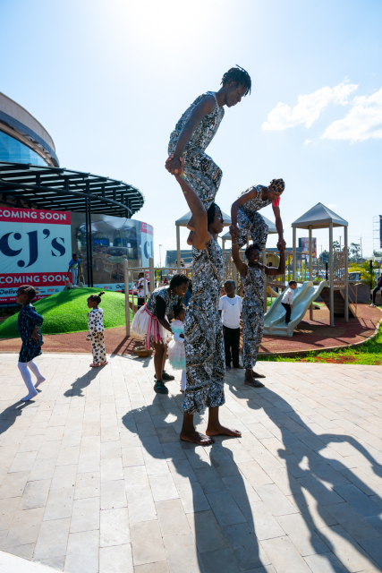 Performers form a human pyramid near a playground outside the shopping mall.