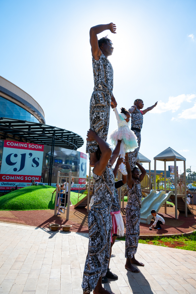 Performers form a tall human pyramid outside the shopping mall.