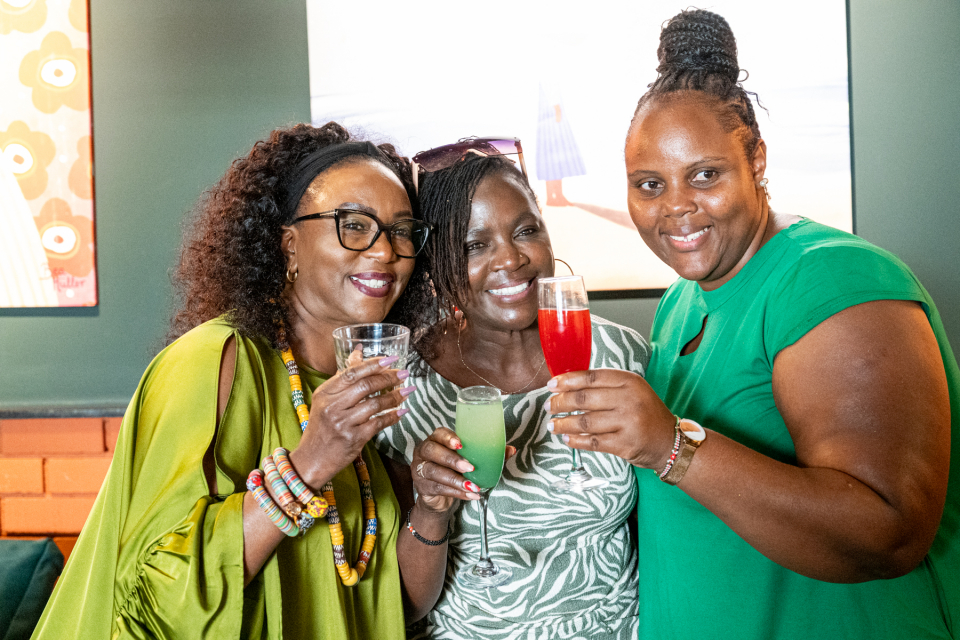 DZ6 1605 Three smiling women hold up colorful drinks for the camera