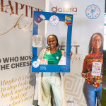 DZ6 1694 Smiling woman poses inside a blue book-themed photo frame while another woman holds a matching sign.