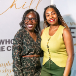 DZ6 1766 Two smiling women pose together in front of a white backdrop with literary-themed text and mall branding.