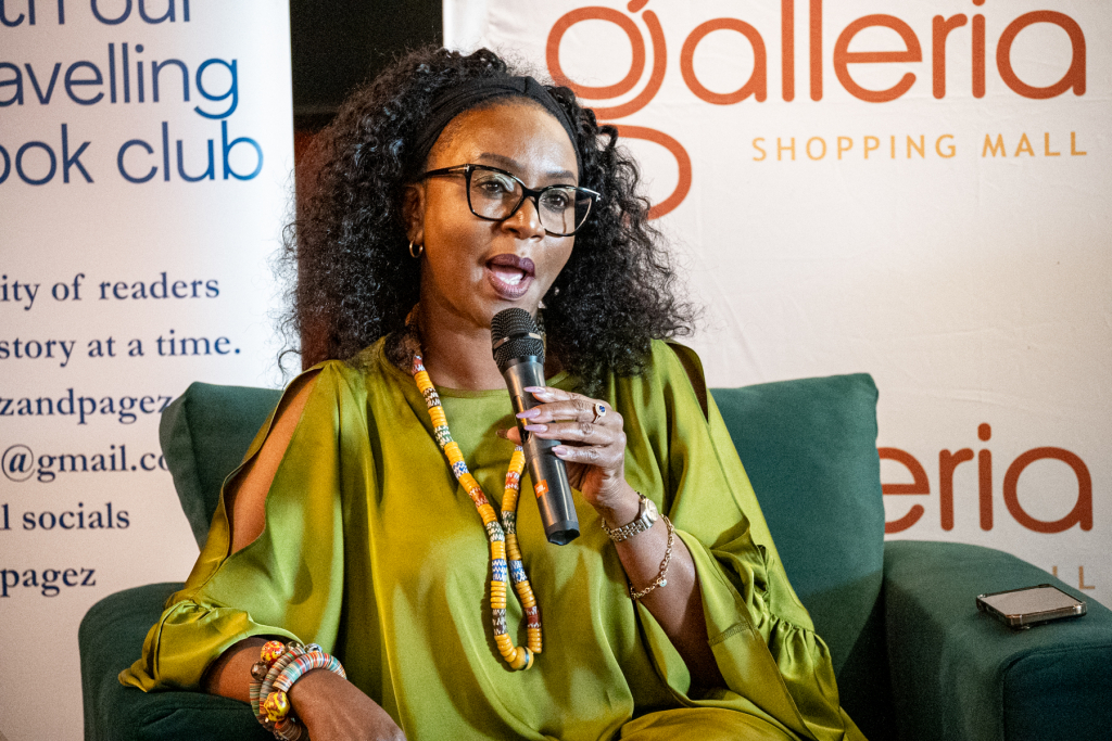 Woman in green speaks into a microphone while seated at a Galleria Shopping Mall event.