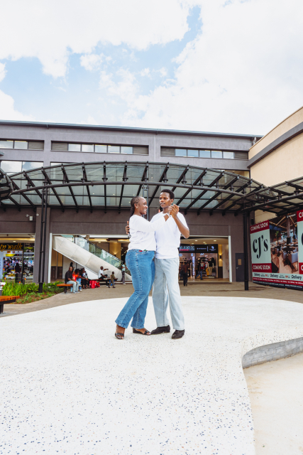 Two dancers perform together in the open mall courtyard beneath a glass canopy.