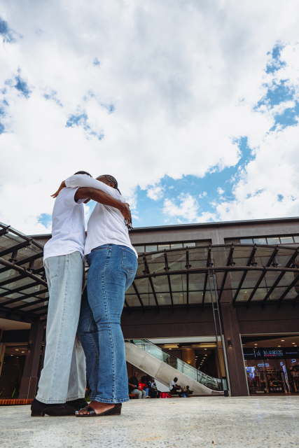 Two dancers share a close partnered move in the mall courtyard beneath the canopy.