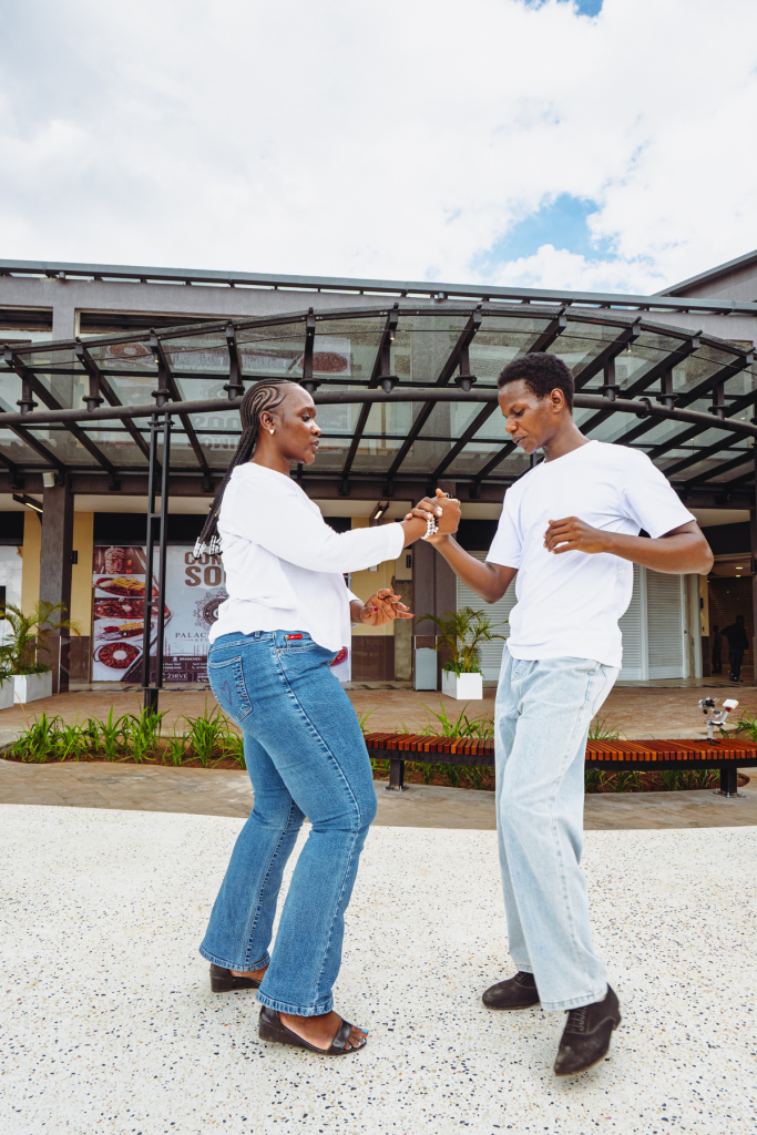 A woman and man dance while holding hands in the mall courtyard