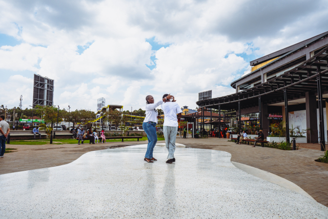 Two dancers perform in the center of a wide outdoor mall plaza