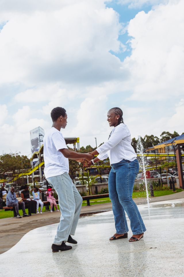 Dancers Performing Beside the Fountain Two dancers hold hands while performing on the wet courtyard surface beside the mall fountain.