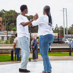 Dancers Facing Each Other on the Plaza Two people in white shirts face each other with raised hands on an outdoor plaza